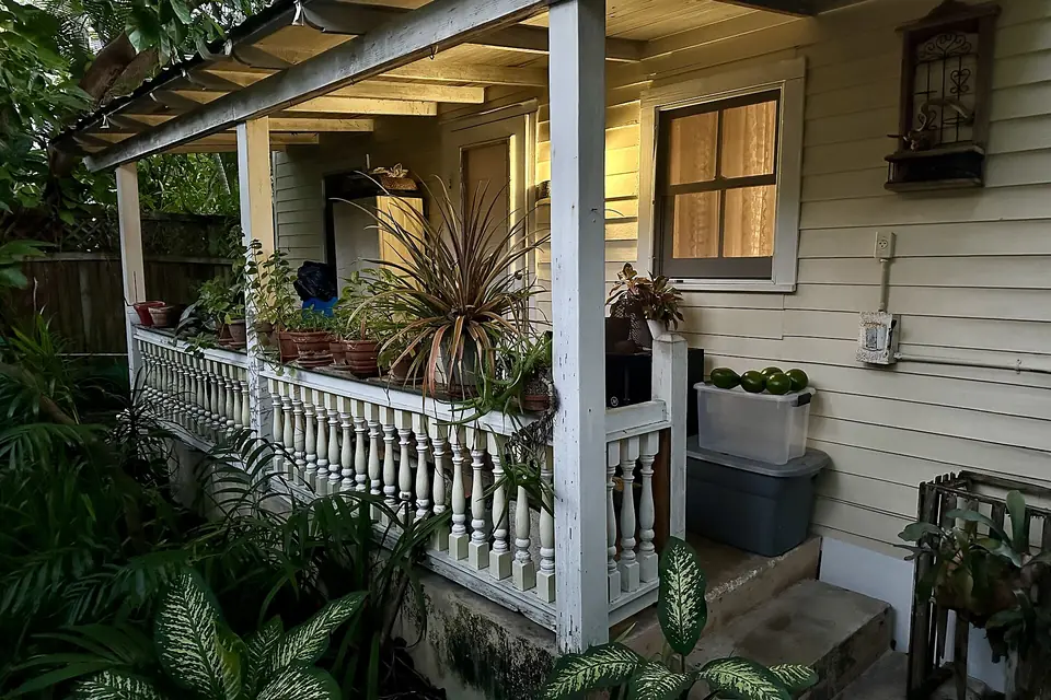 The front porch of a Key West conch house with plants and a porch light