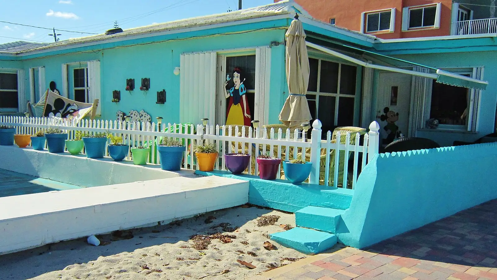 A turquoise beach cottage with a picket fence on the Hollywood Beach Broadwalk, Florida